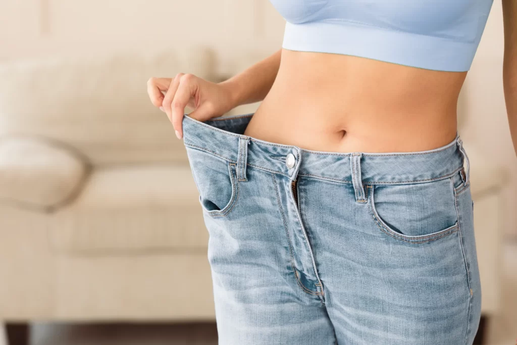 slim woman shows off her too big jeans utc